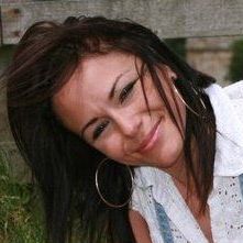 A woman wearing hoop earrings and a white shirt is smiling.