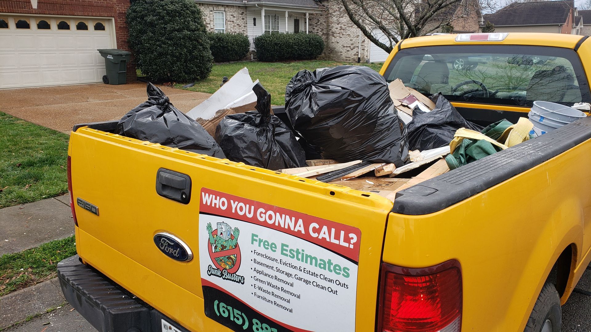 Yellow pickup truck filled with trash and debris; marketing logo on the side.