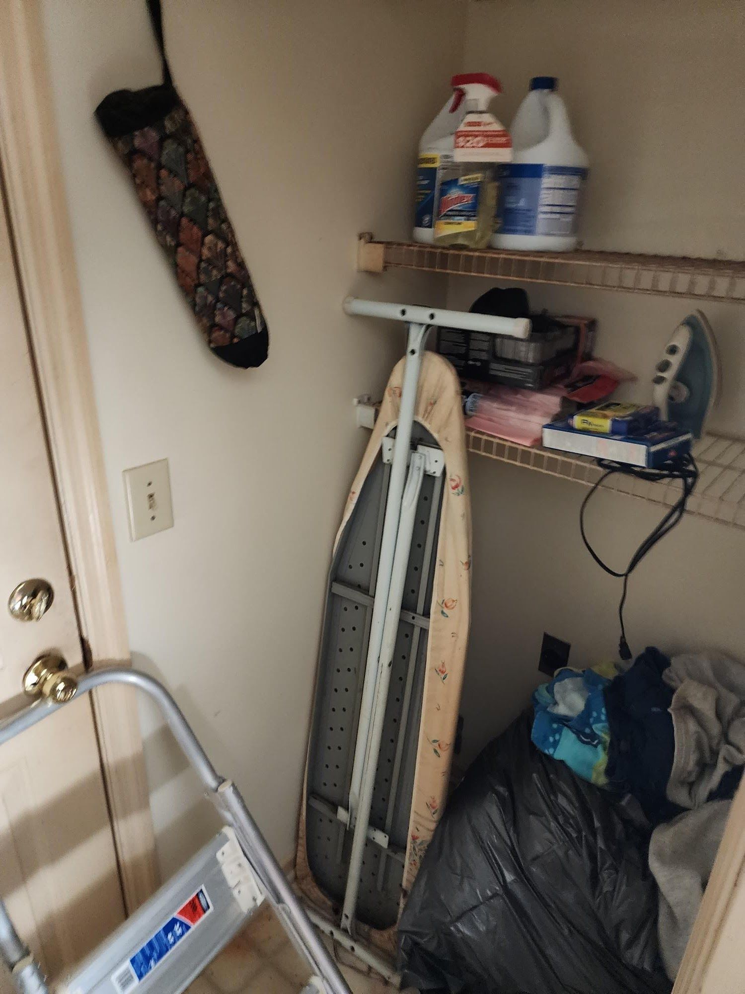 A closet with a ladder and an ironing board