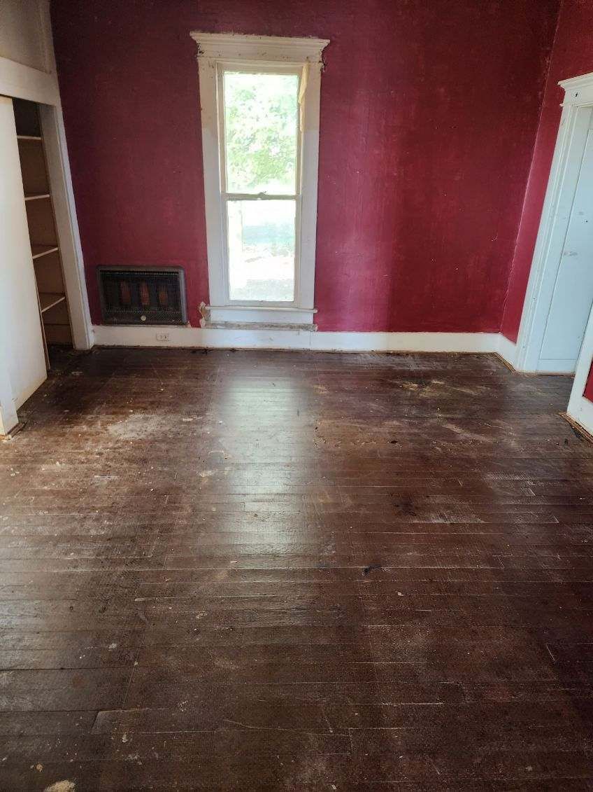An empty room with red walls and a wooden floor.