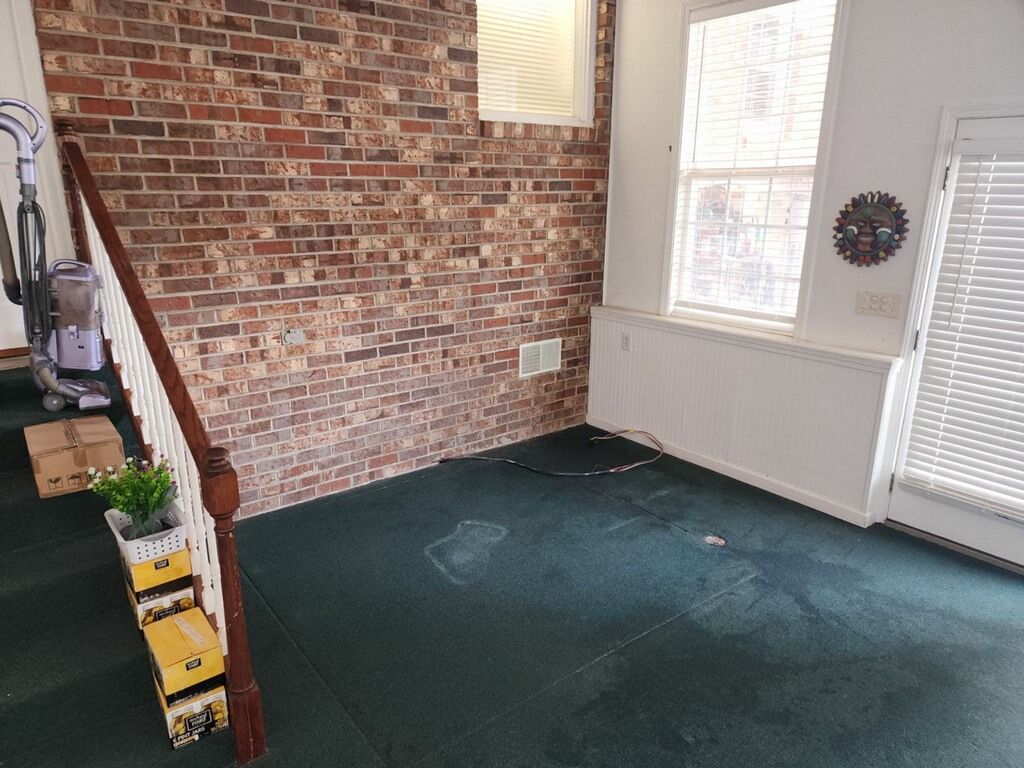 An empty living room with a brick wall and stairs.