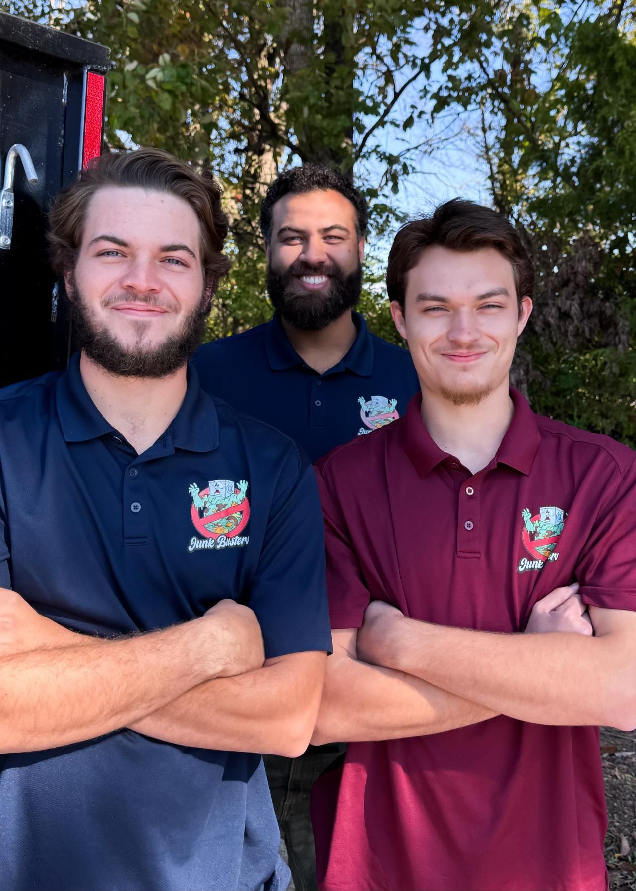 Three people with arms crossed, wearing polo shirts with a logo.