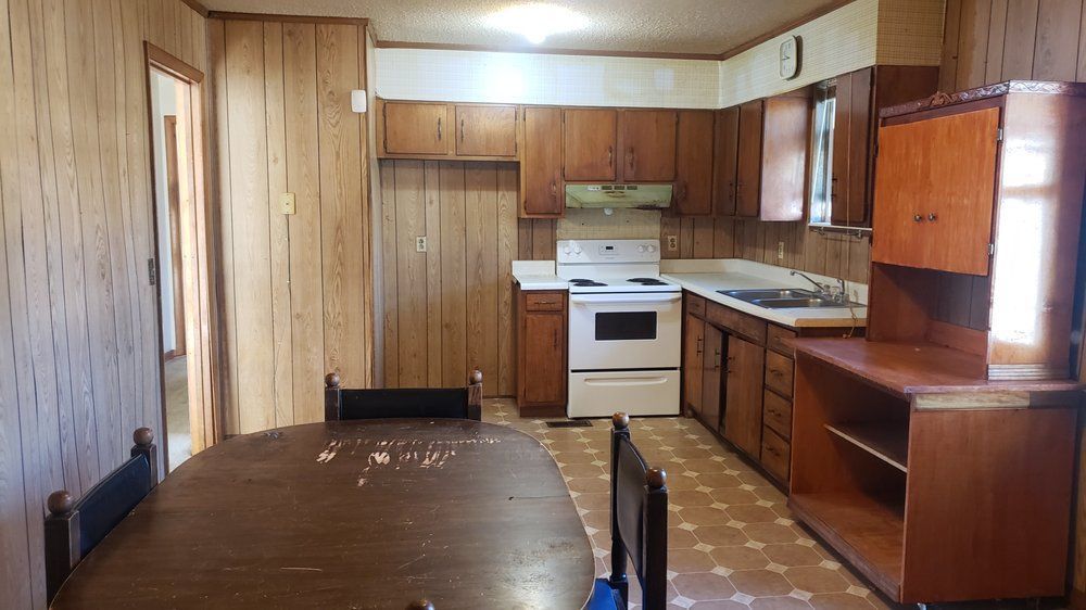 A kitchen with wooden cabinets , a table and chairs.