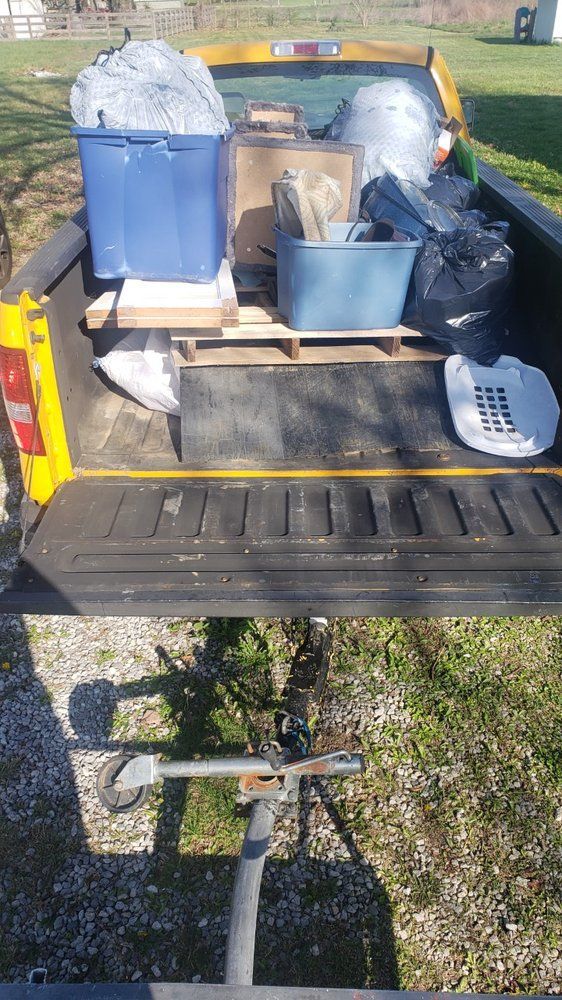 The back of a truck filled with lots of trash and boxes.