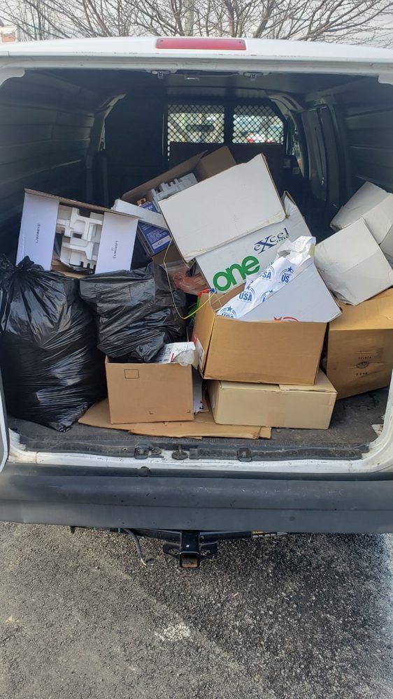 The back of a van is filled with boxes and trash bags.