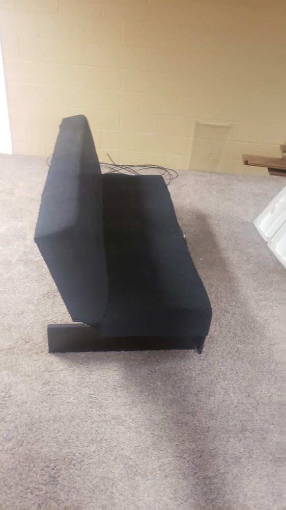 A black box is sitting on top of a carpeted floor.