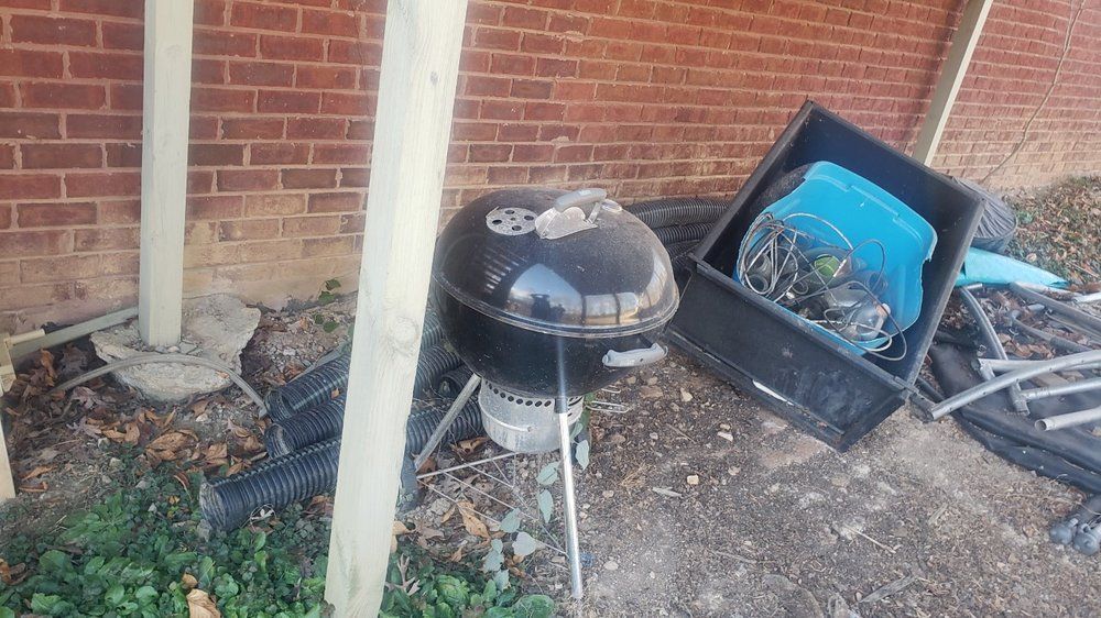 A barbecue grill is sitting on the ground next to a brick wall.