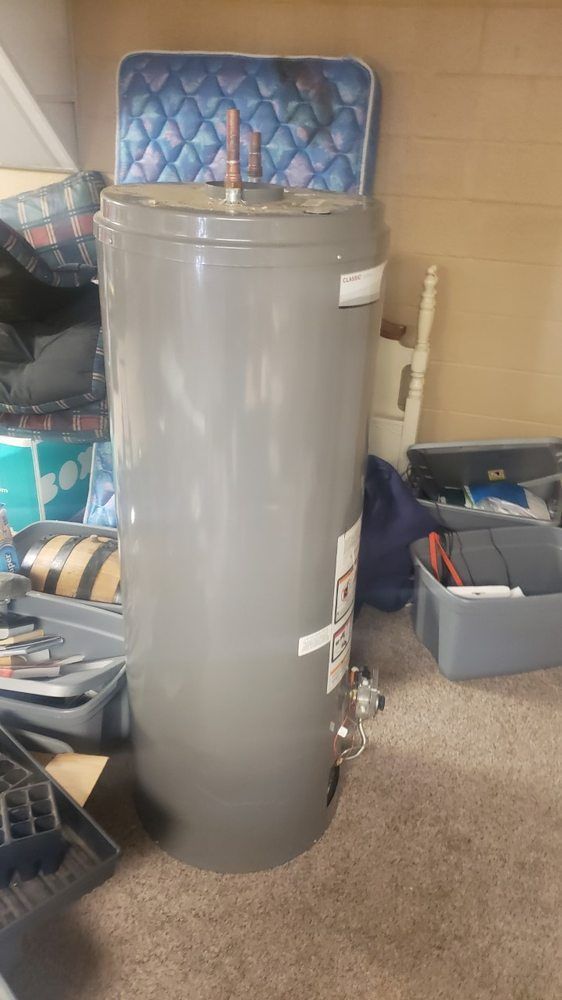A large gray water heater is sitting on the floor in a room.