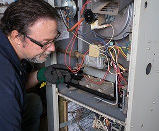Furnace Repairs — Repairman Checking On Furnace  in Hillsboro, MO