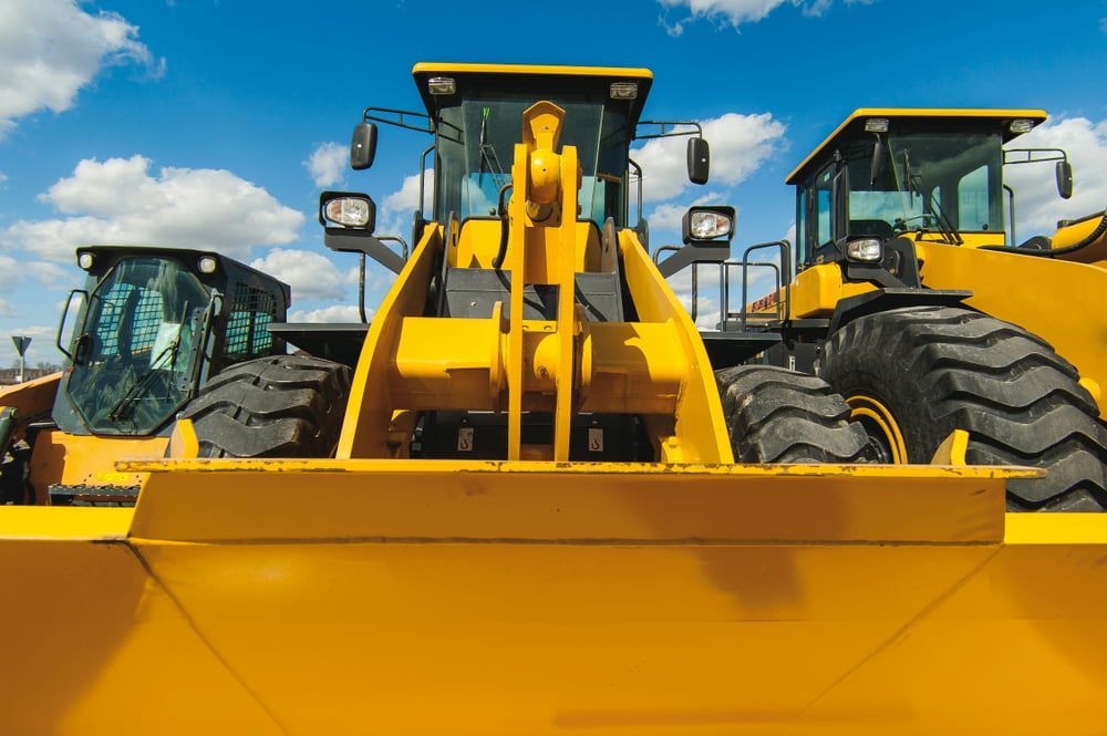A Couple of Yellow Tractors Are Parked Next to Each Other — Glass in Wollongong, NSW