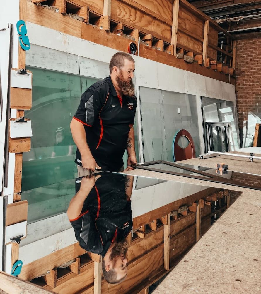 A Man is Measuring a Piece of Glass With a Triangle Measuring Tool — Langson Glass in Wollongong, NSW 