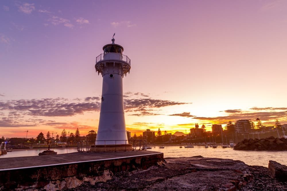 A Lighthouse in The Middle of A Body of Water at Sunset — Glass in Wollongong, NSW
