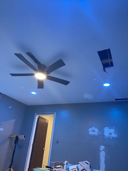 Blue-painted room with ceiling fan, recessed lights, open door, and a ladder against the wall.