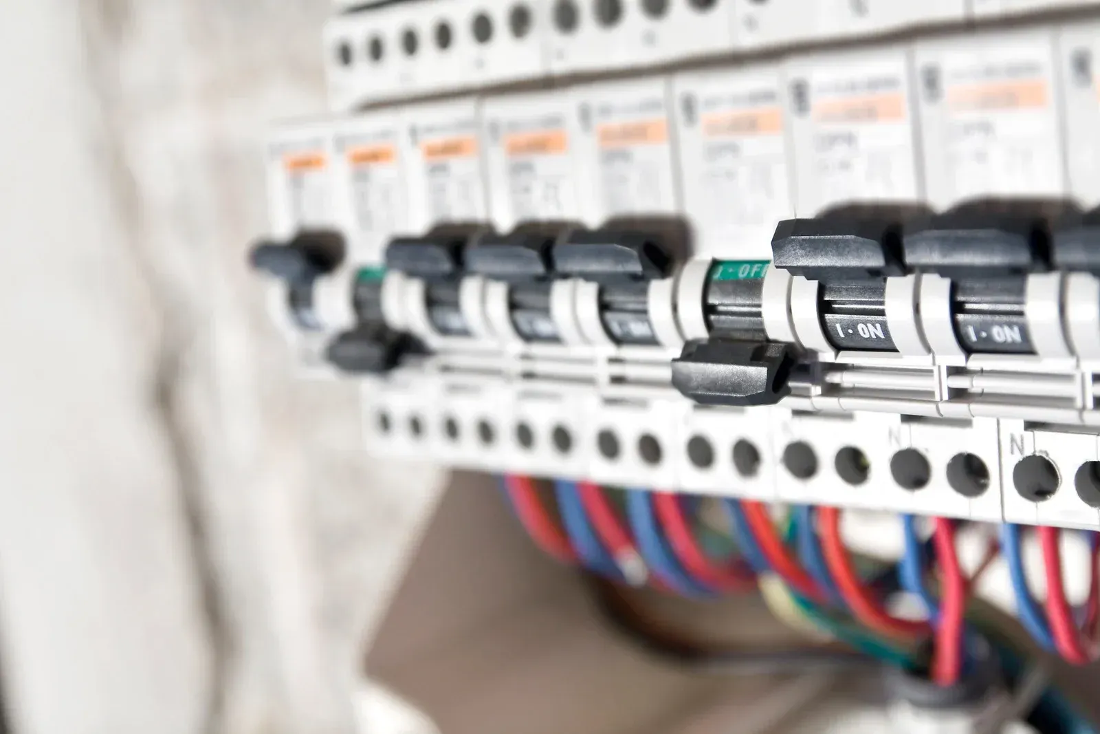 Circuit breaker panel with rows of switches and colorful wires in an electrical cabinet