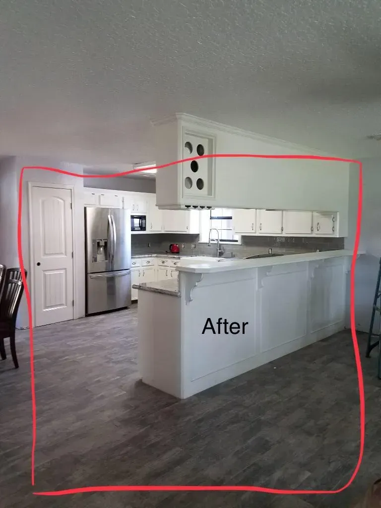 White kitchen renovation with island, countertops, cabinets, and new flooring.