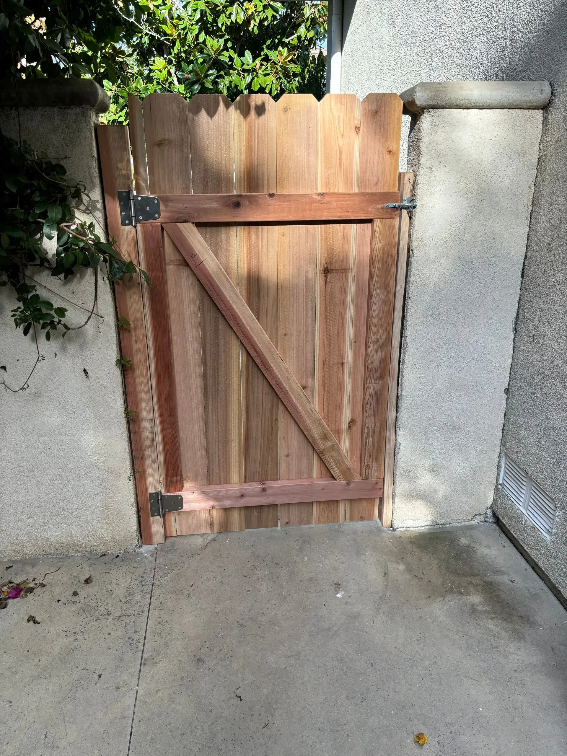 Wooden gate in a concrete entrance, with diagonal brace.