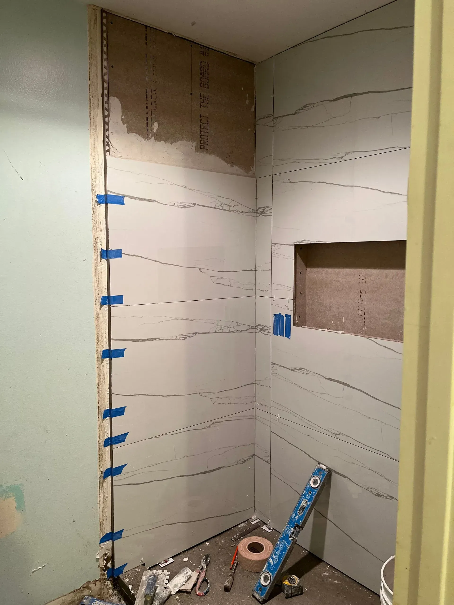 Bathroom shower renovation with cement board walls marked for tile placement.
