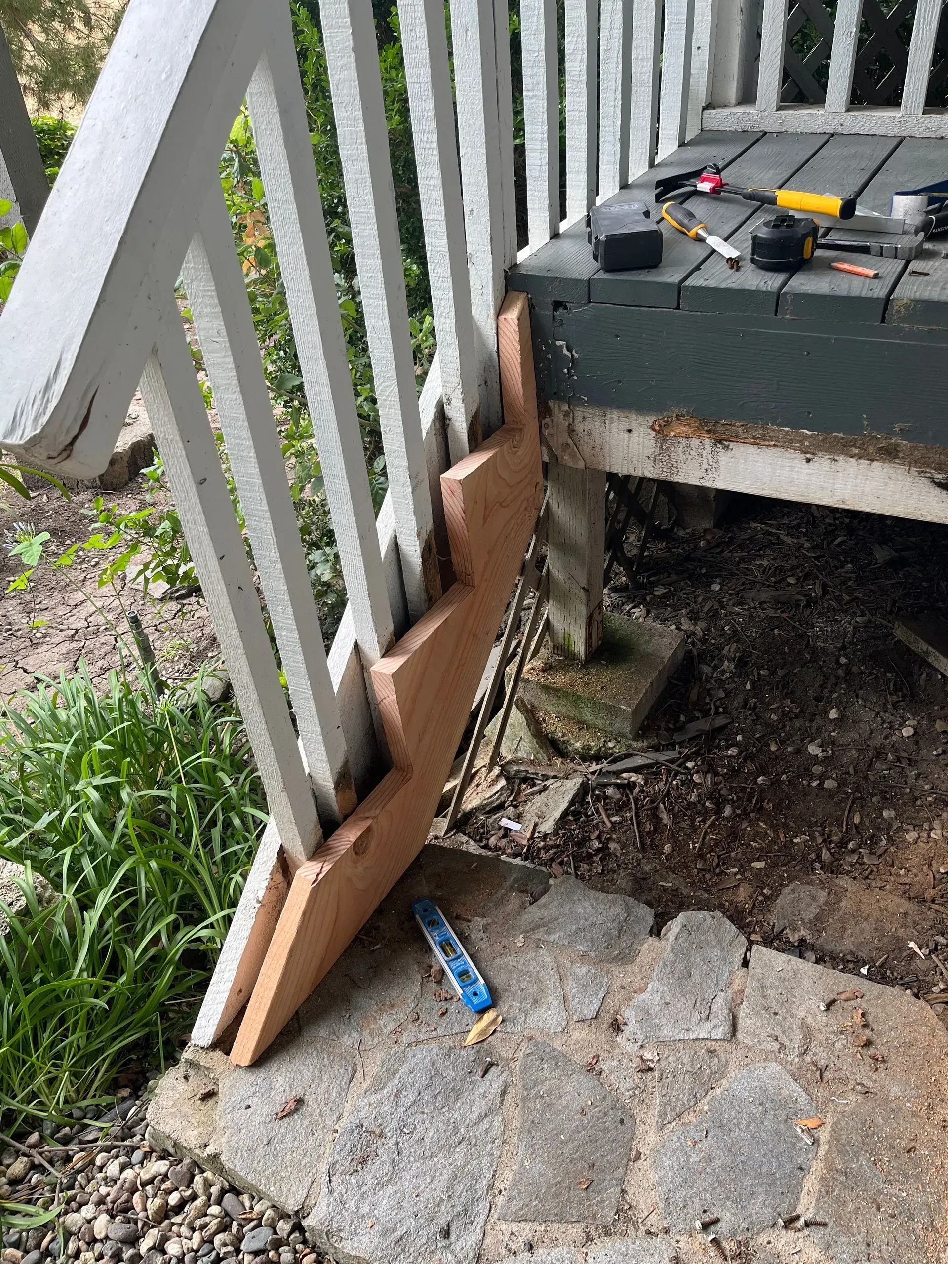Wooden steps added to a porch railing, extending the handrail downward.
