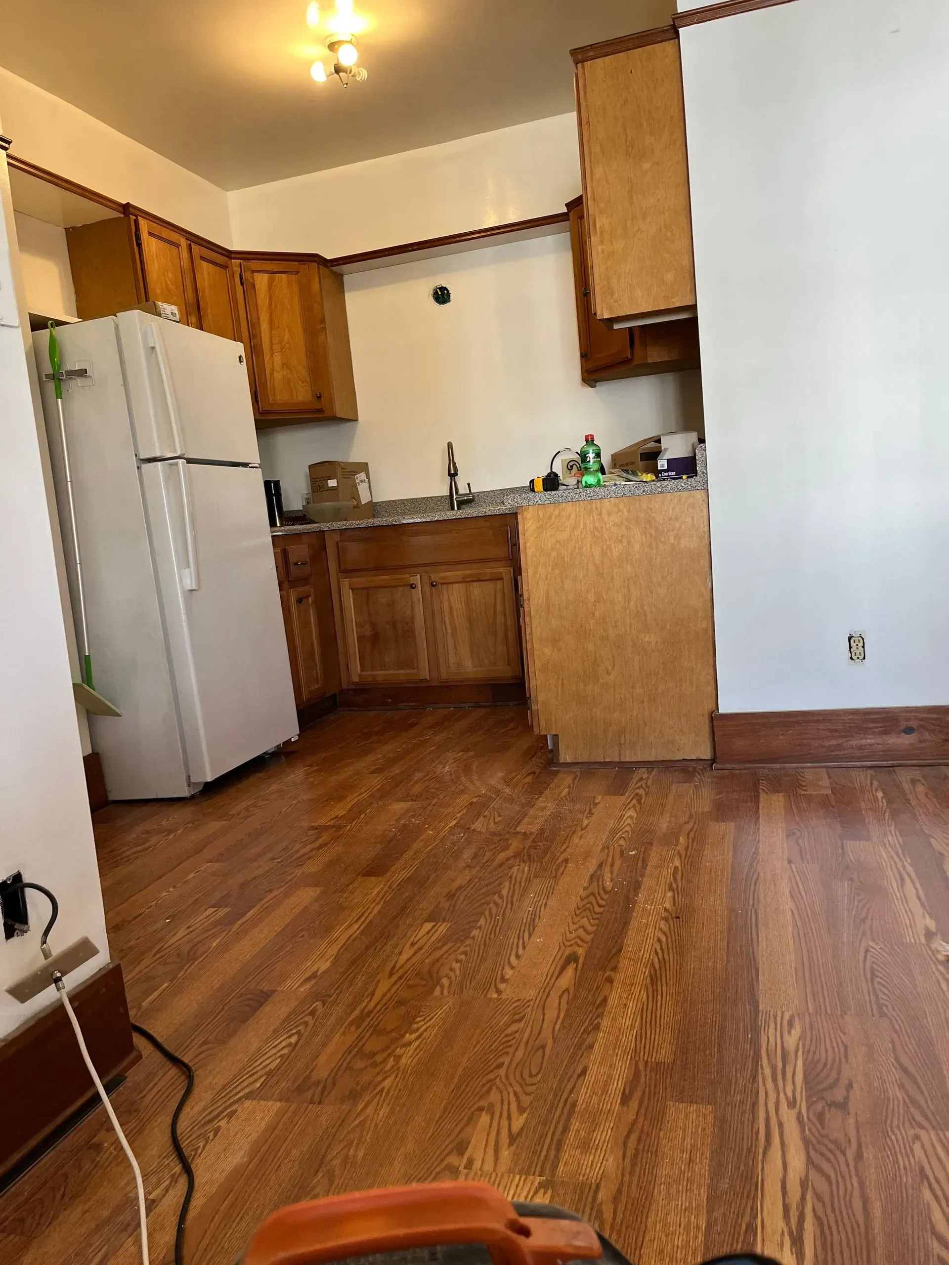 Kitchen with wood cabinets, white refrigerator, and wood floor.
