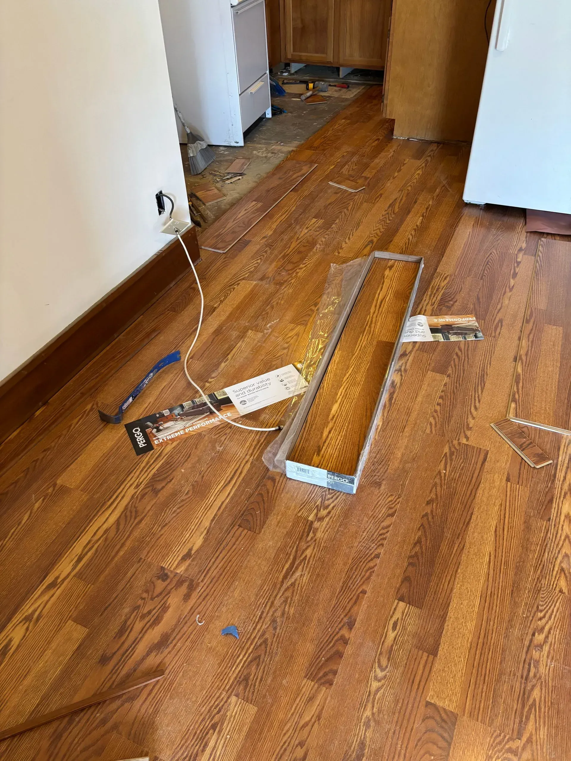 Wooden flooring installation in progress; tools and materials scattered on the floor.
