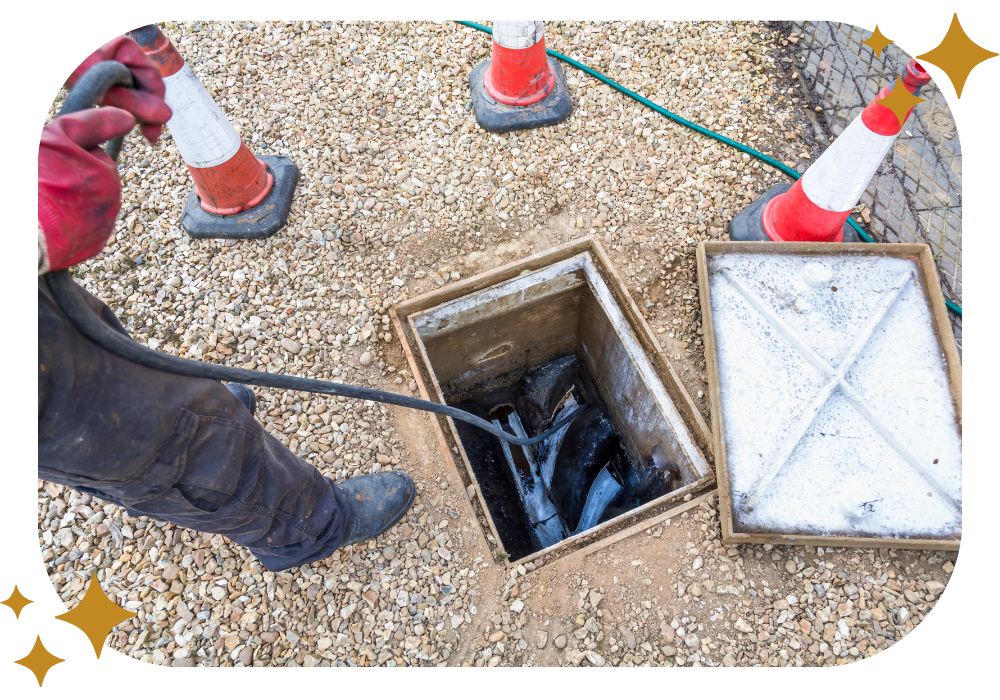 A man is cleaning a drain with a hose.