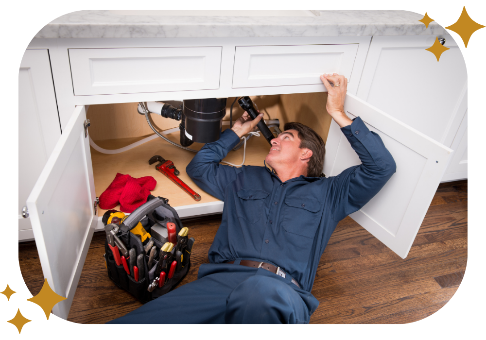 A plumber is laying on the floor fixing a sink.