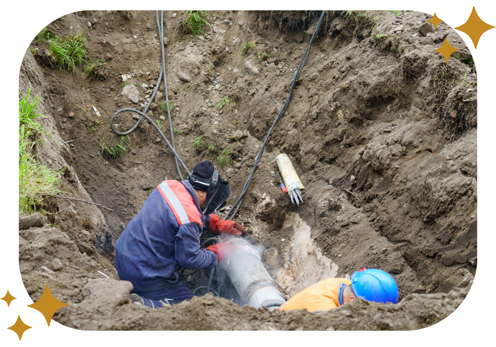 A man is working on a pipe in the dirt.