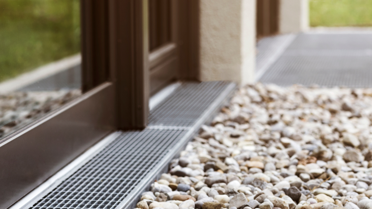 A metal grate is on the ground next to a sliding glass door.