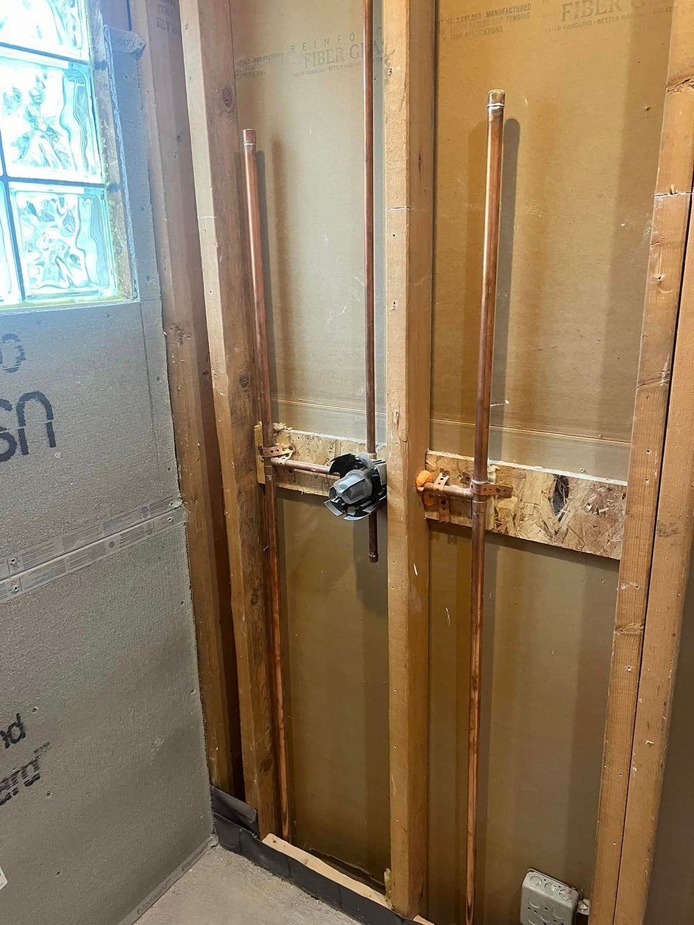A bathroom with copper pipes coming out of the wall.