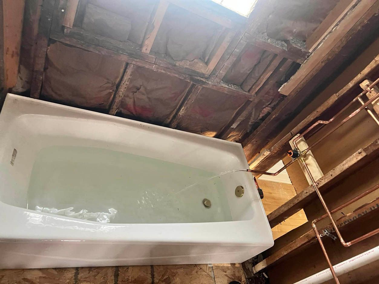 A bathtub is sitting under a wooden ceiling in a bathroom.