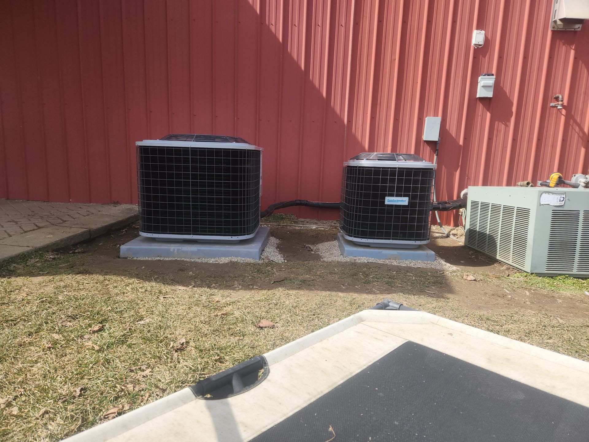 Two air conditioners are sitting in front of a red building