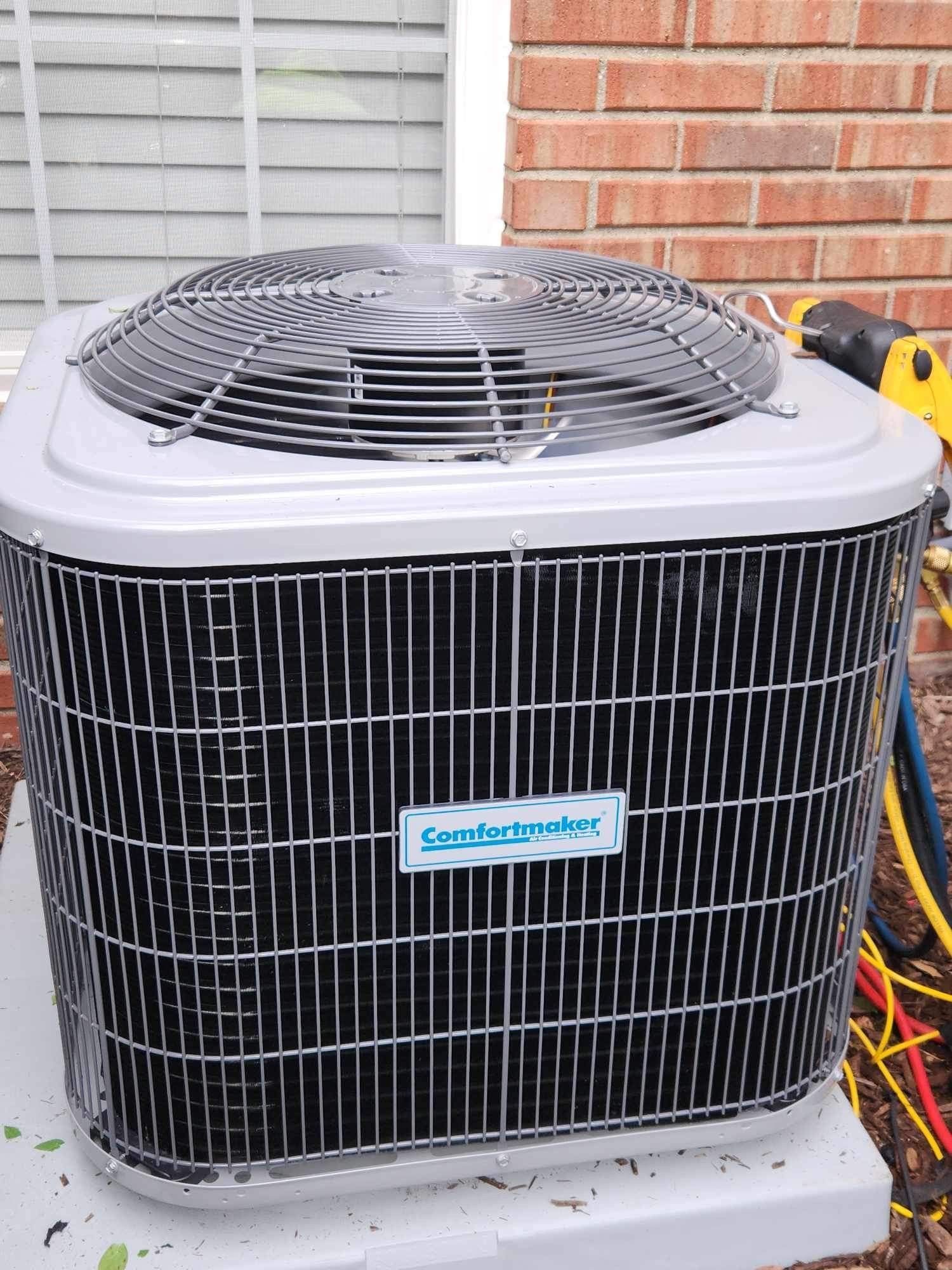 An air conditioner is sitting outside of a brick building