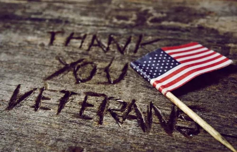 Small American flag placed beside engraved “Thank You Veterans” message on rustic wood in Austin, TX
