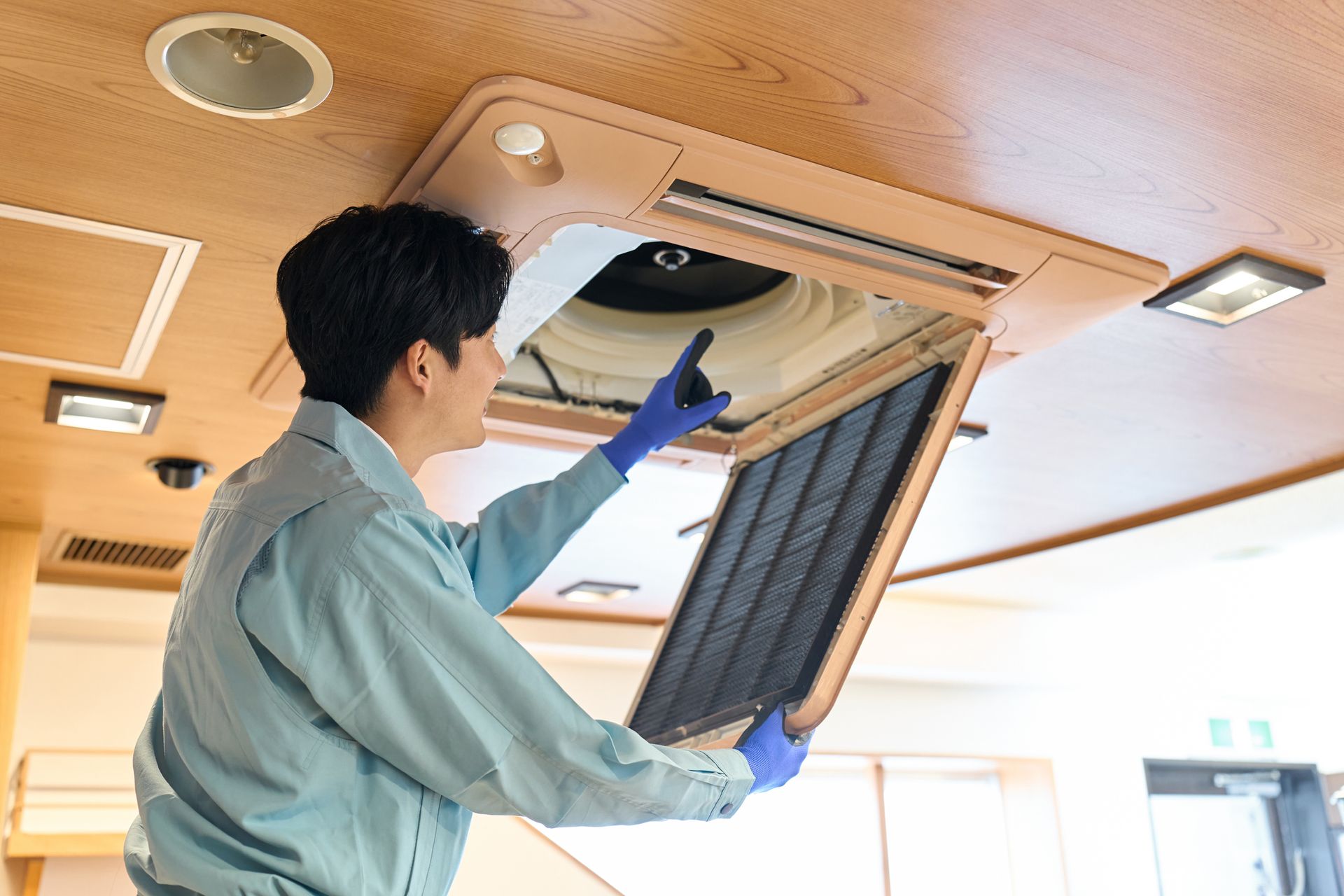 A young man checking the air conditioning equipment in a restaurant A young man checking the air conditioning equipment in a restaurant