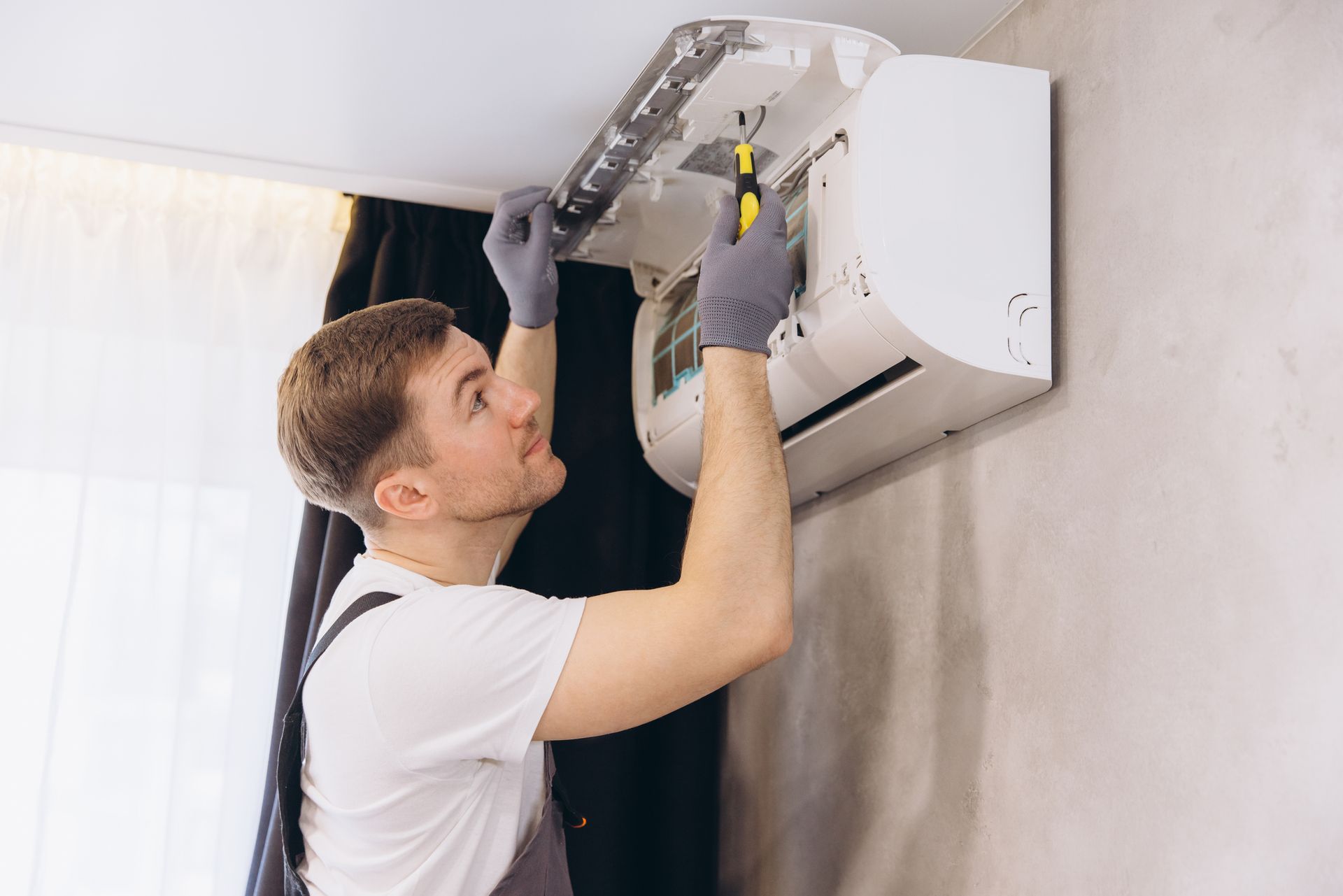 Image of a professional contractor repairing a modern air conditioner unit.