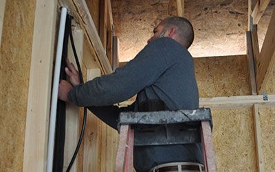 A man is standing on a ladder working on a wall.