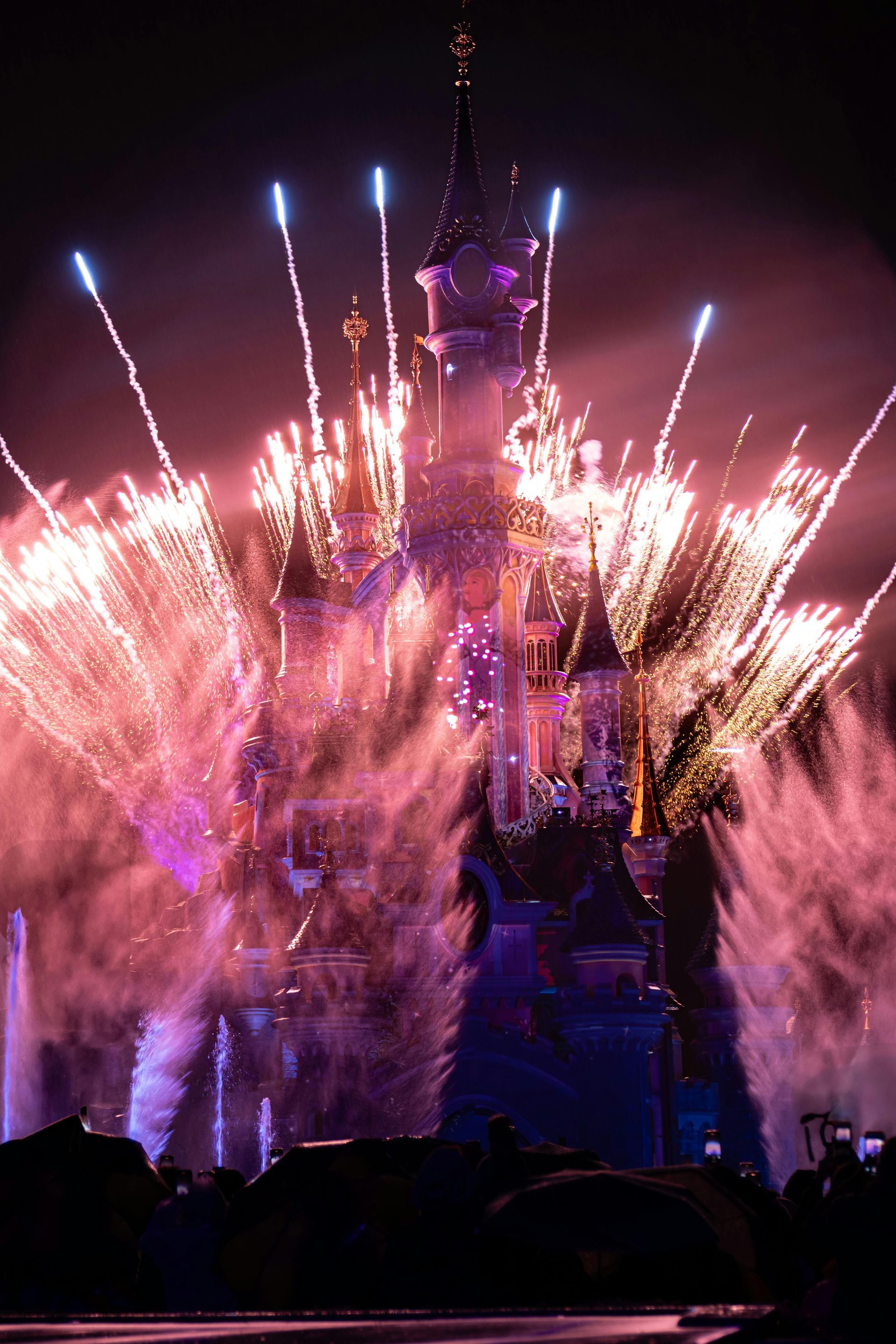 A camera on a gimbal held in front of a Disney park building with people and trees under a blue sky.