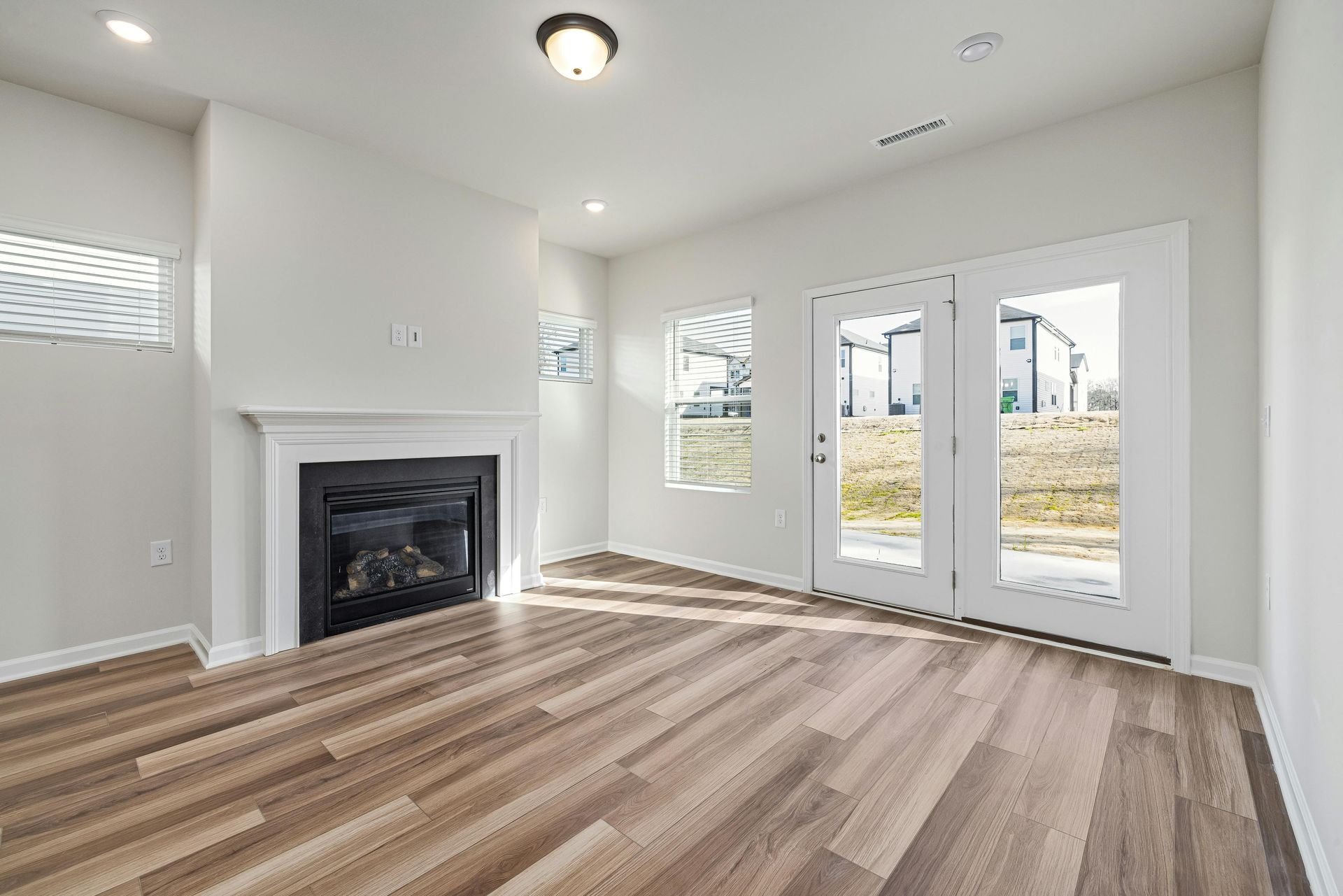 An empty living room with hardwood floors and a fireplace.