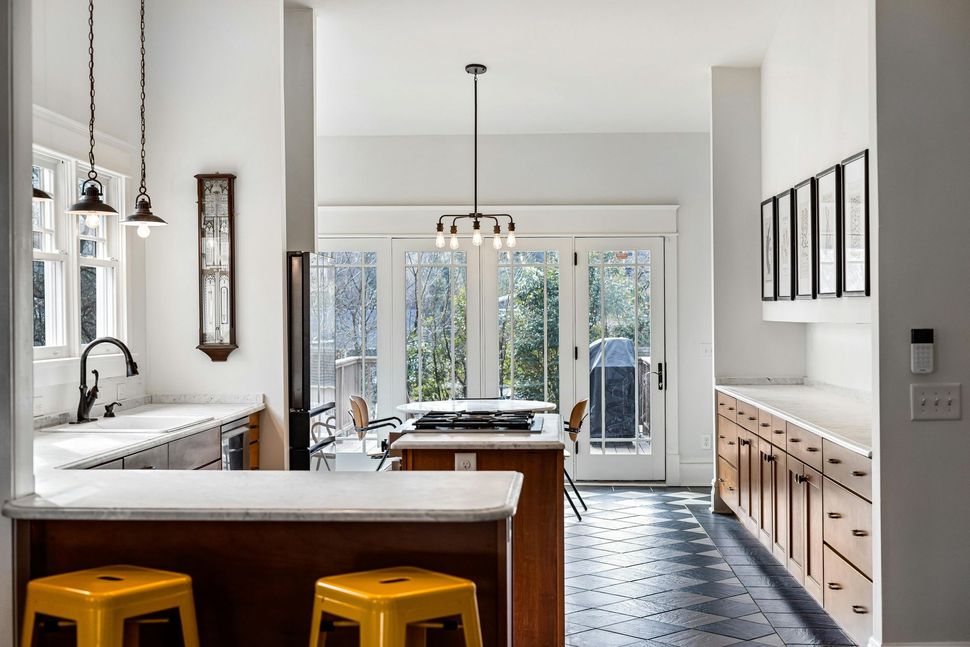 A kitchen with a large island and two yellow stools.