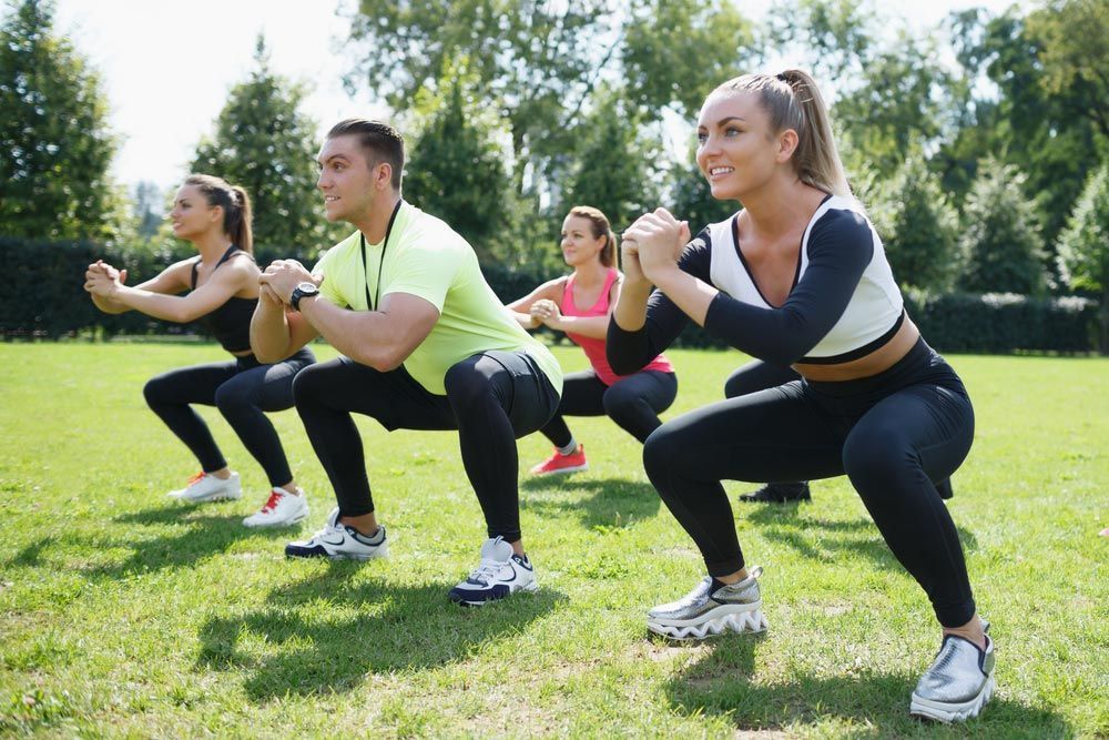 Group Of People Are Squatting On The Grass In A Park — Kym Connolly Wellness Coach in Svensson Heights, QLD