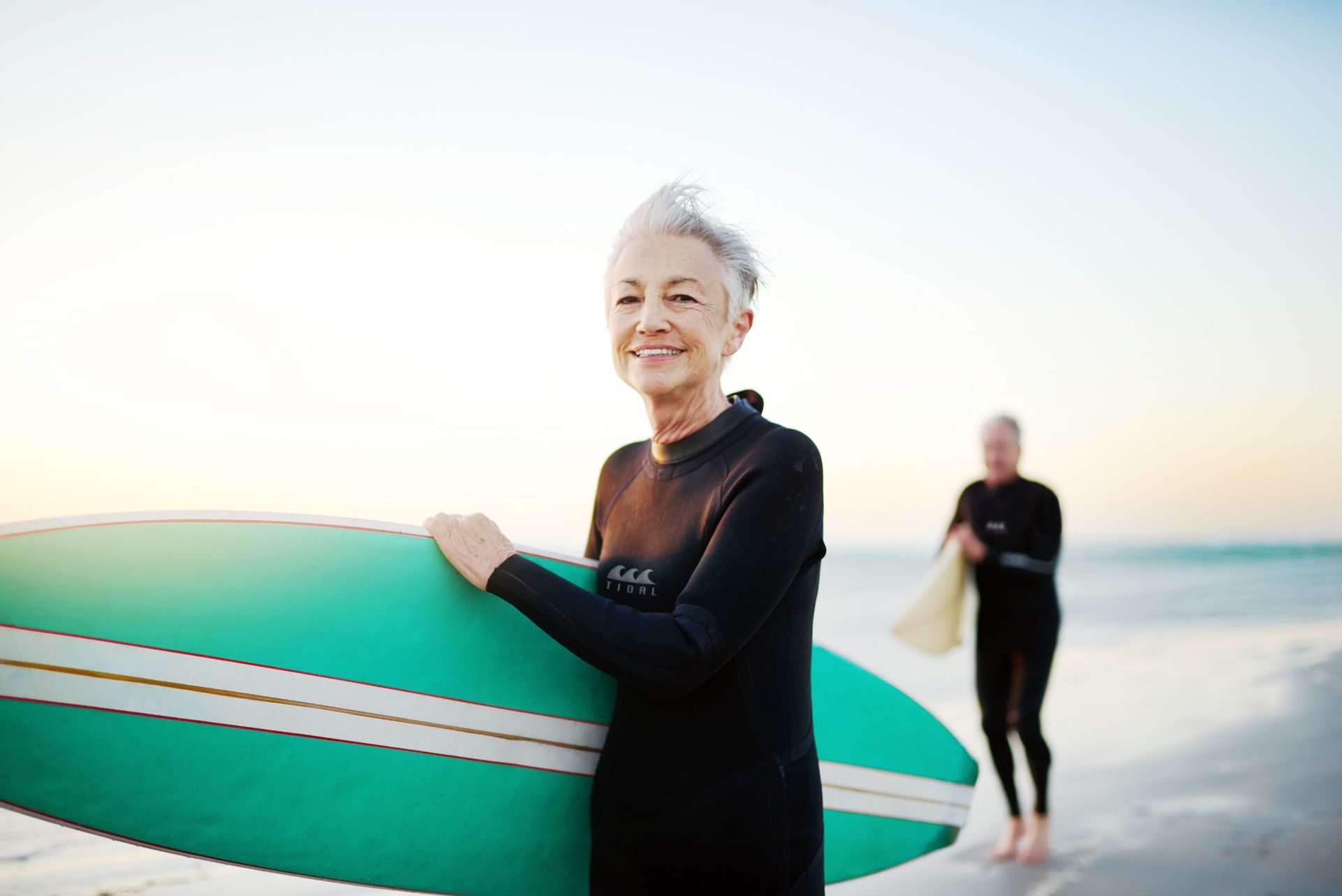 An Older Lady Holding A Surf Board — Kym Connolly Wellness Coach in Svensson Heights, QLD