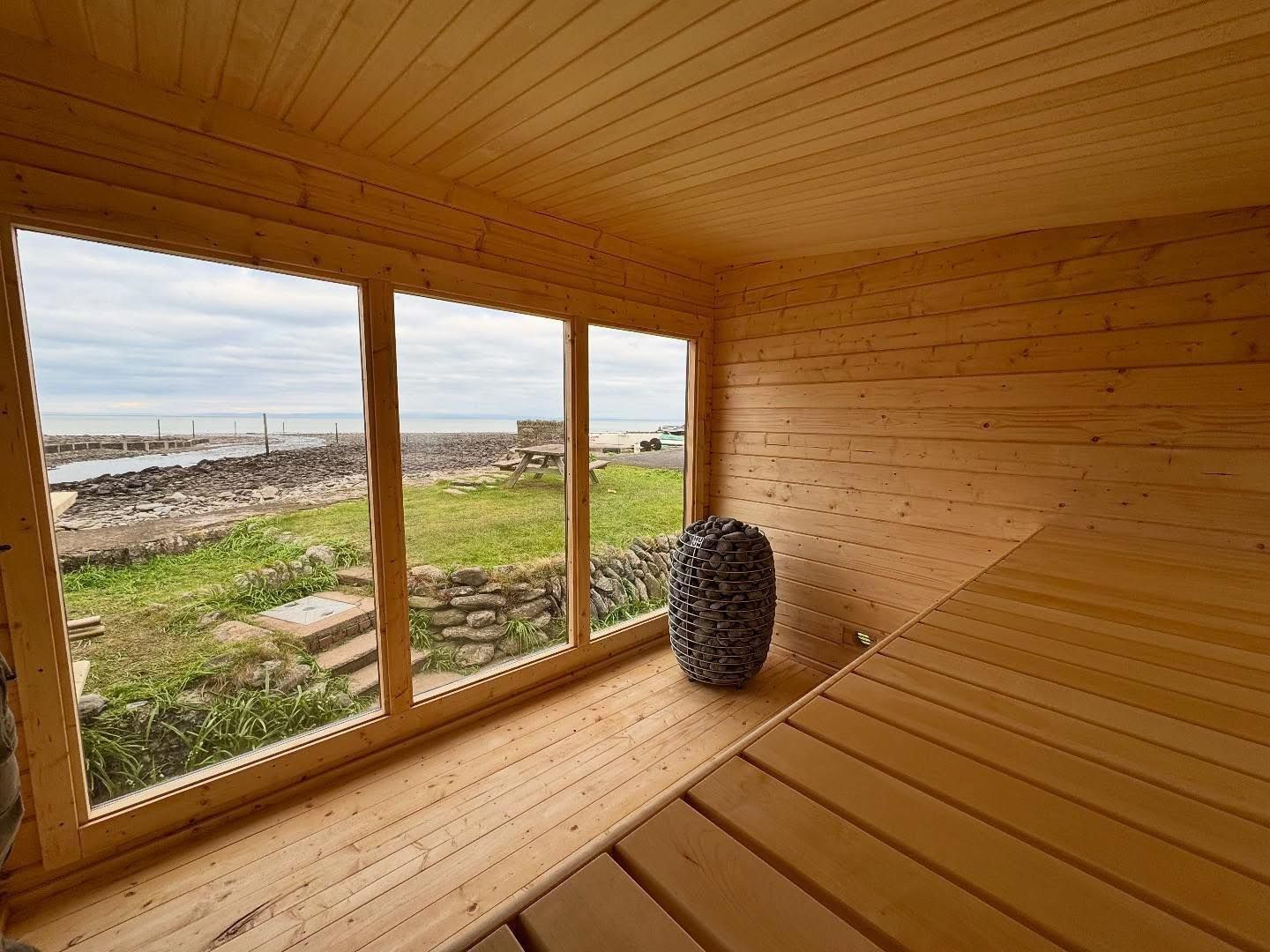 The interior of a wooden sauna looking out to the seaside.