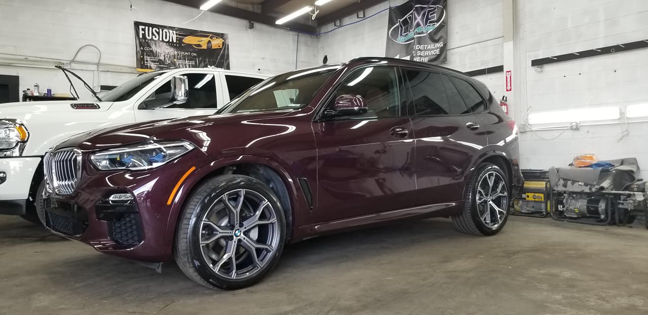 A maroon SUV parked inside a garage; another white vehicle and tools are in the background.