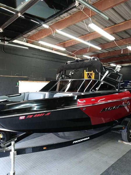 Black and red motorboat on a trailer inside a building.