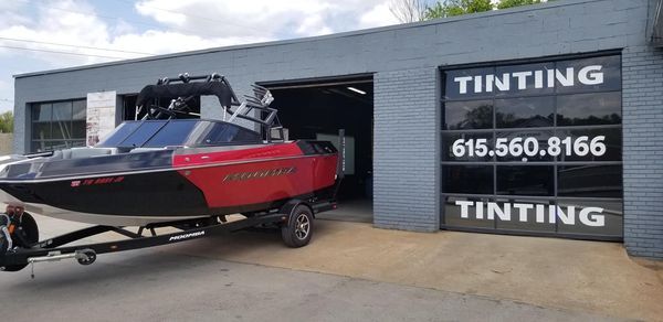A red and black boat on a trailer in front of a shop with 
