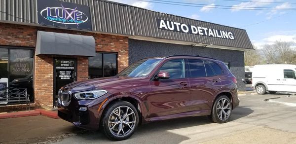 A burgundy SUV parked outside an auto detailing shop with the words 