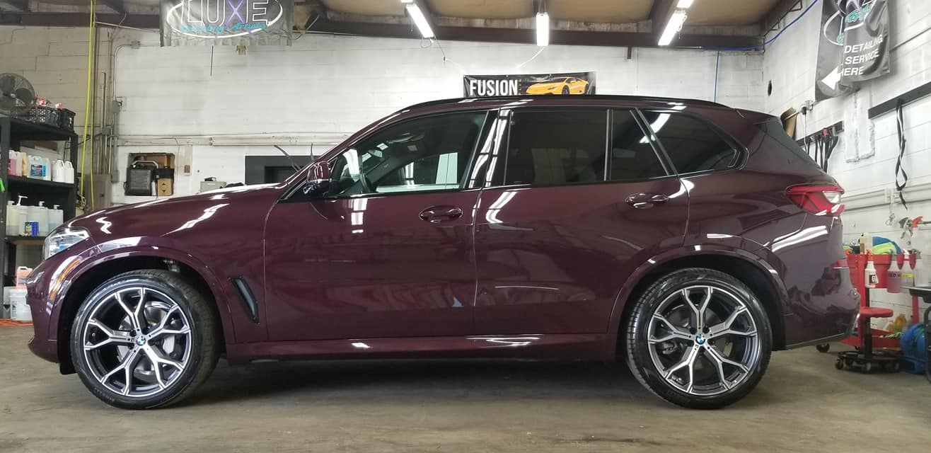 Burgundy SUV with chrome wheels in a garage.