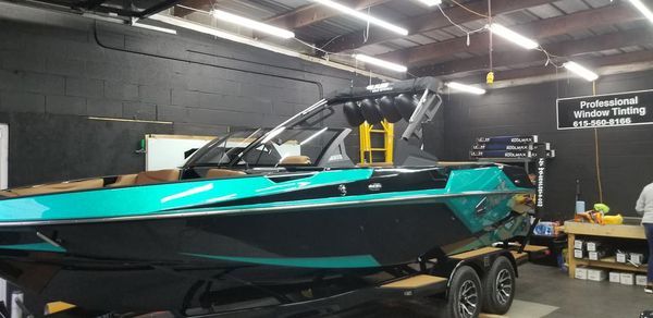 A teal and black boat on a trailer inside a workshop. 
