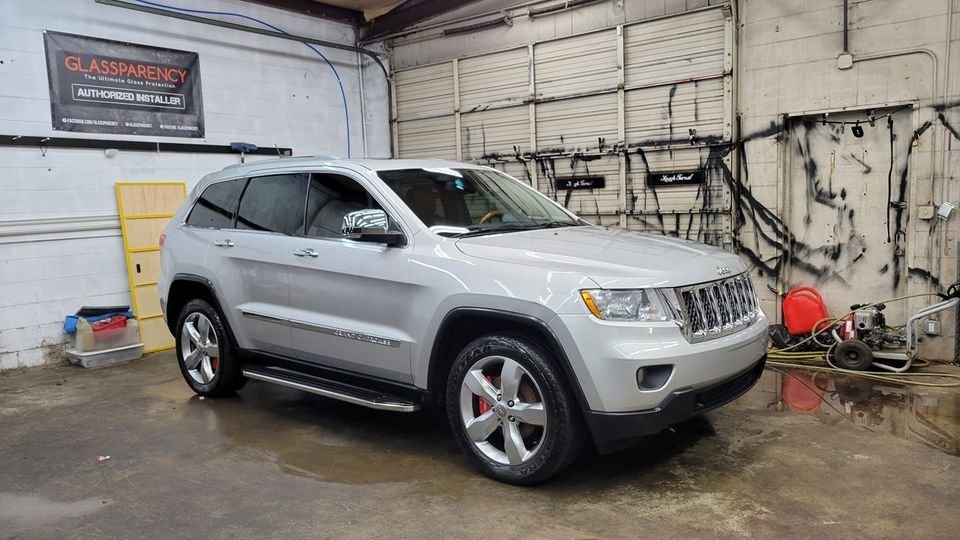 Silver Jeep Grand Cherokee in a garage.