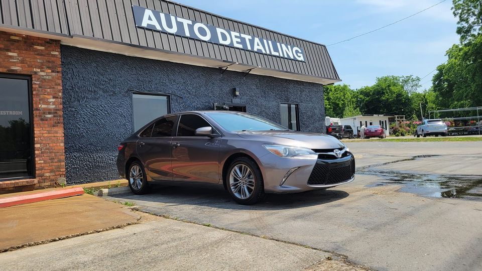 A purple car parked outside an auto detailing shop on a sunny day.